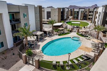 A pool surrounded by a fence and chairs in a courtyard.
